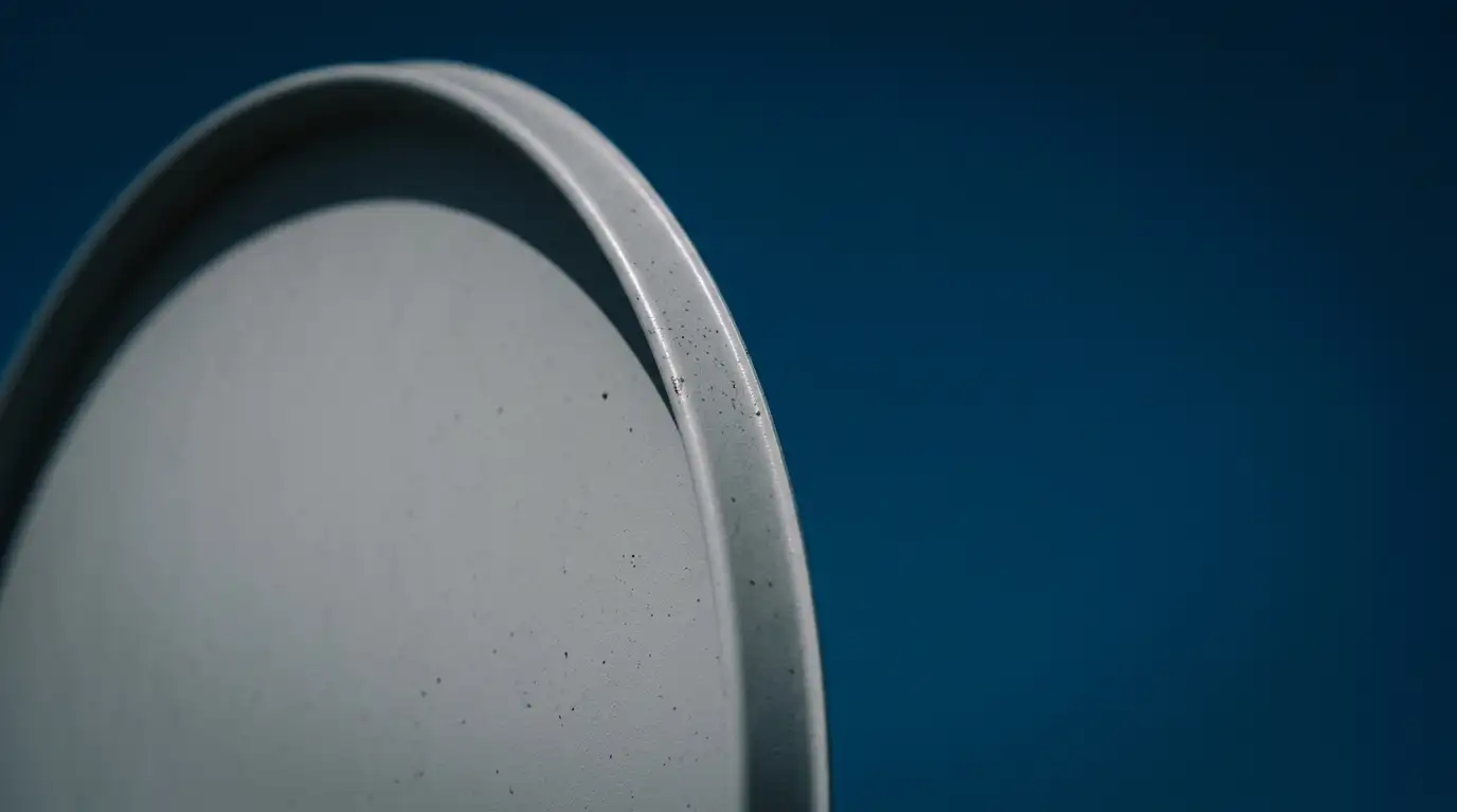 Close-up of a satellite dish rim against a deep blue sky